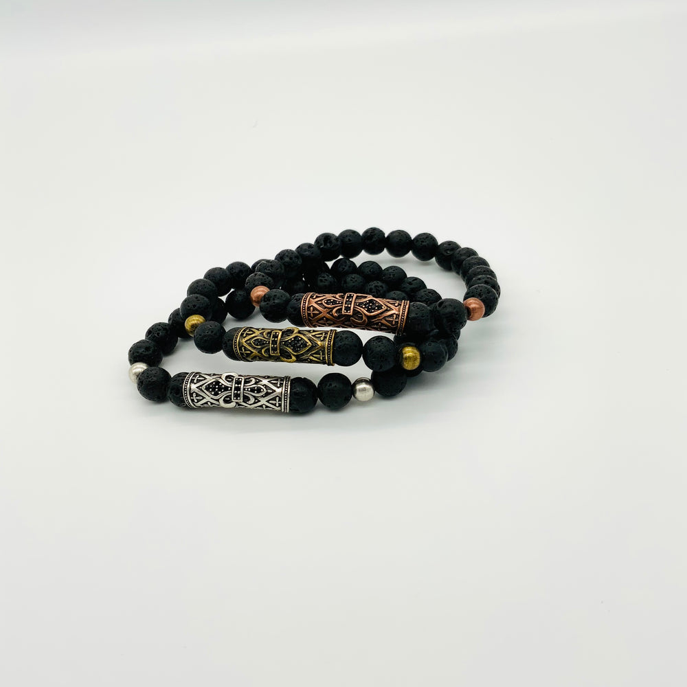 
                  
                    3 stacked black lava rock bracelets with a large accent bead in center. Silver on bottom, gold in the middle, and bronze on top
                  
                