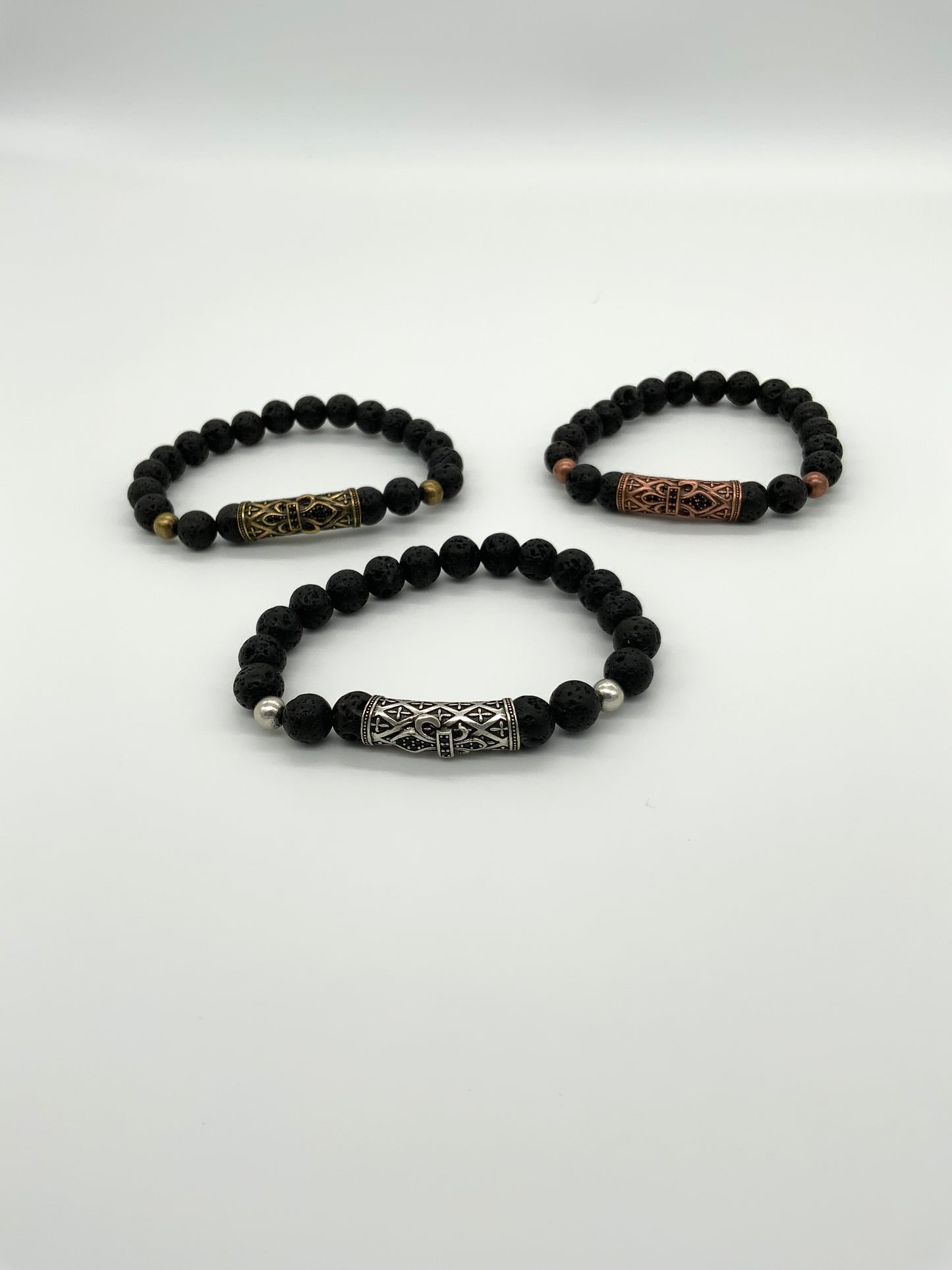 
                  
                    3  black lava rock bracelets with a large accent bead in center displayed in a triangle. Silver center front, gold back left, and bronze back right
                  
                
